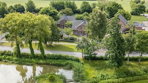 Ein Wohngebiet mit Teich, Bäumen und einem Haus mit Satteldach.