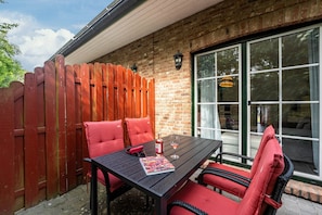 An outdoor patio with a table, chairs, and a red fence.