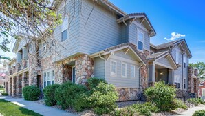 A multi-story residential building with stone accents, a covered porch, and a well-maintained front yard. - Seasonal Pool, Balcony: Quiet & Cozy Aurora Condo! (Aurora)