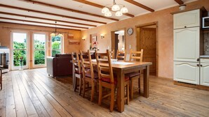 A dining area with wooden chairs, a wooden table, and a ceiling with exposed beams. - Holiday Home 'Ferienhaus Sundperle' with Private Terrace, Private Garden and Wi-Fi (Stralsund)