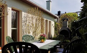 Eine Terrassengaststätte mit Tisch, Stühlen, einem Blumentopf und einem Steinkamin.