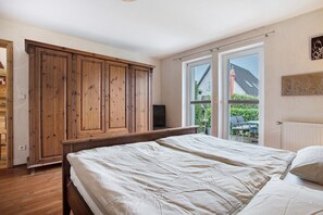 Ein Schlafzimmer mit zwei Betten, einem Holzschrank und einer Glastür zum Balkon.