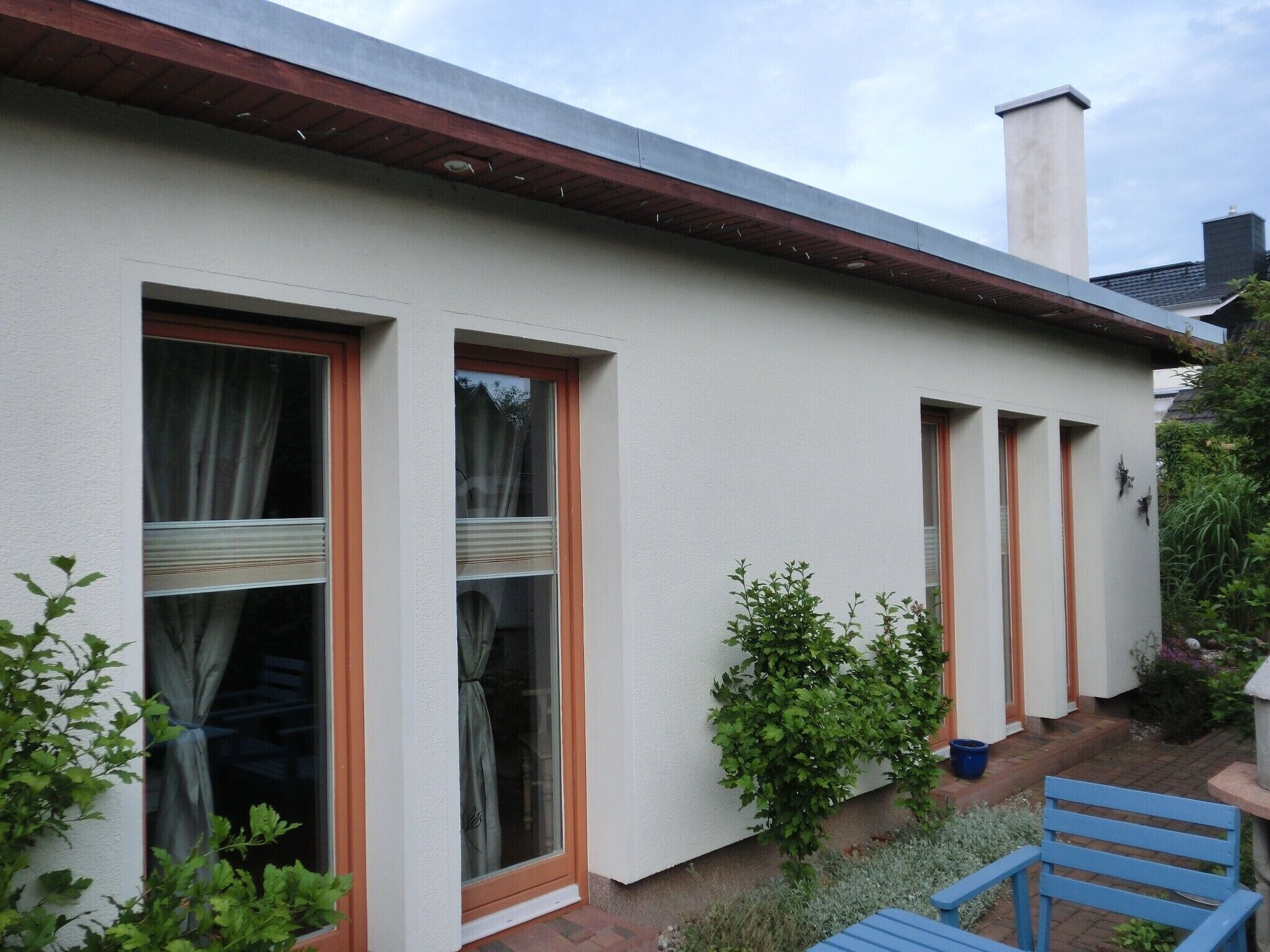 A building with multiple windows, a visible chimney, and a small garden area with a bench.