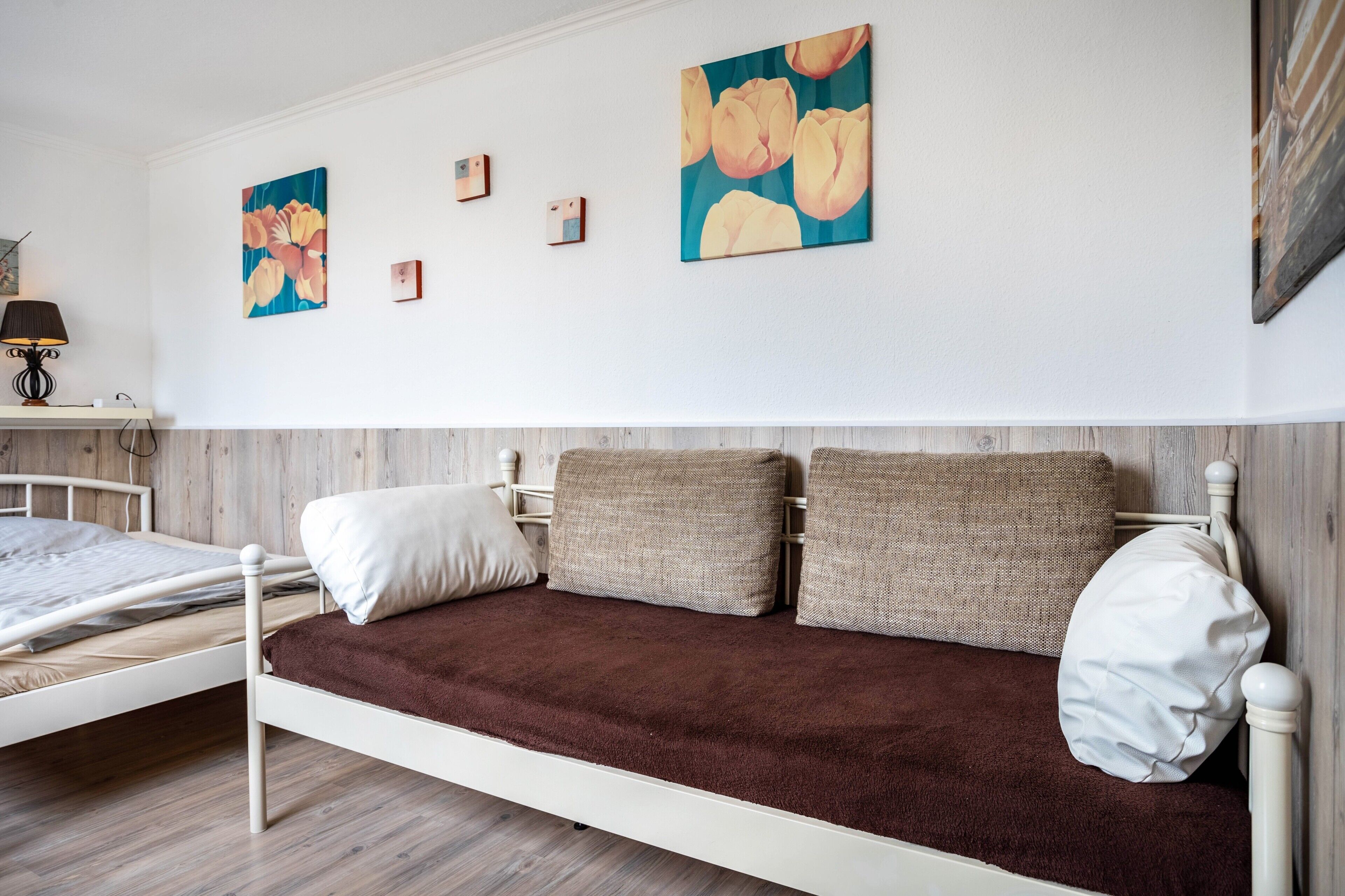 Una cama con un edredón marrón, una almohada blanca y dos almohadas color beige.