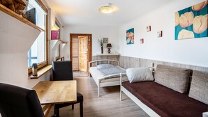 A room with a bed, a sofa, a wooden table, and a window with shelves. - Apartment 'Ferienwohnung Relax' with Private Terrace, Private Garden and Wi-Fi (Stralsund)