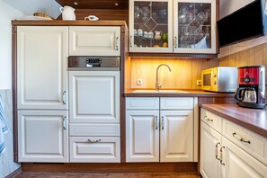 Una cocina con muebles blancos, un microondas, una cafetera y un horno empotrado.