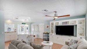 A living room with a TV, sofas, a coffee table, and a ceiling fan. - Waterfront Bungalow with Pool in Matlacha Isles (Matlacha Isles-Matlacha Shores)