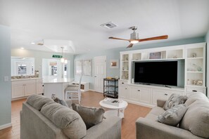 A living room with a TV, sofas, a coffee table, and a ceiling fan. - Waterfront Bungalow with Pool in Matlacha Isles (Matlacha Isles-Matlacha Shores)