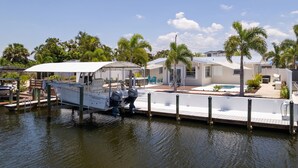 A marina with a boat docked, a dock, and a house with a pool and outdoor furniture. - Waterfront Bungalow with Pool in Matlacha Isles (Matlacha Isles-Matlacha Shores)