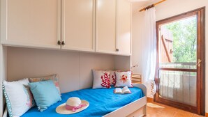 A bedroom with a bed, a wardrobe, and a door leading to an outdoor area.