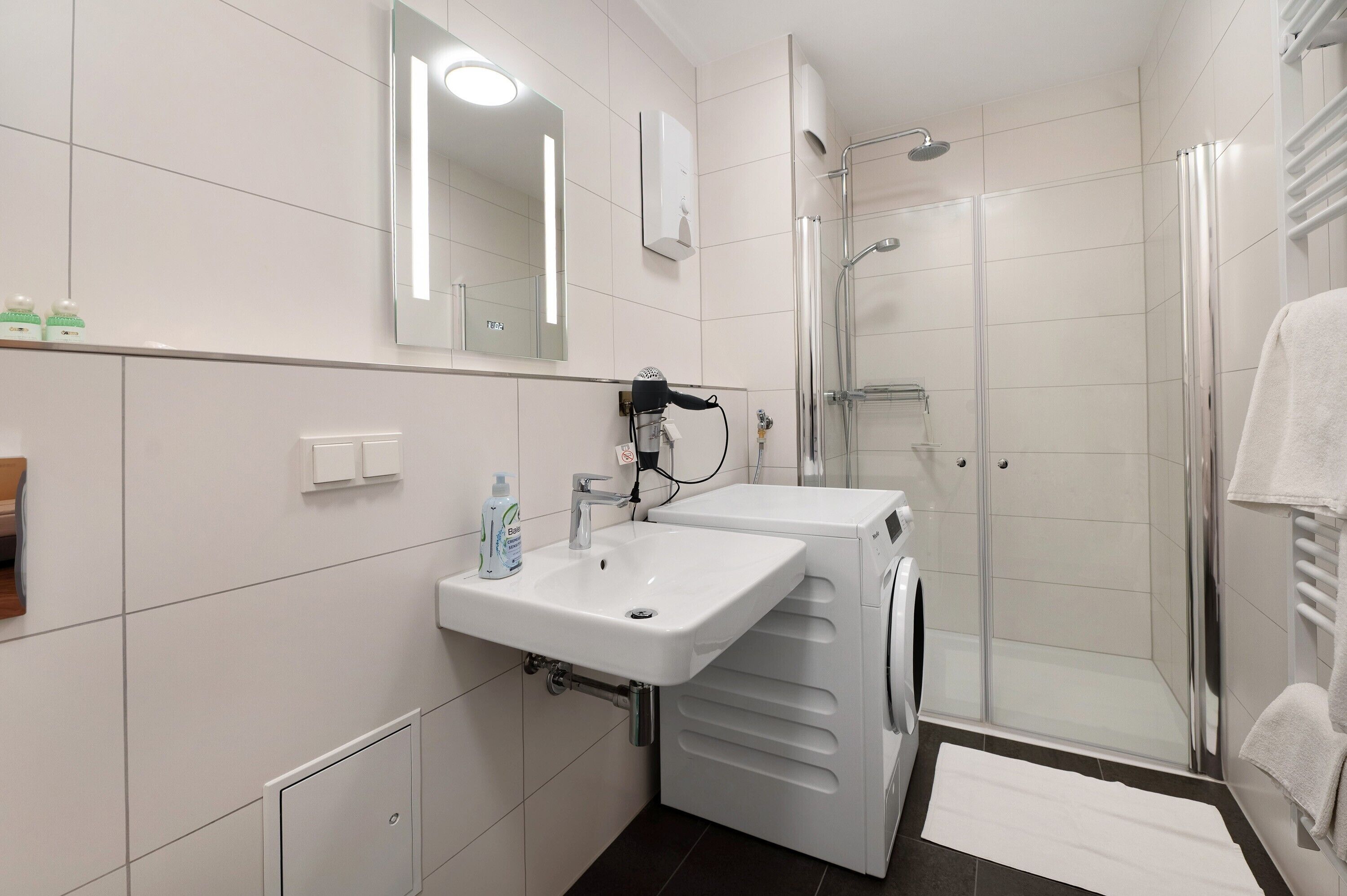 A modern bathroom with a sink, mirror, and a glass-enclosed shower.