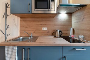 Cozinha moderna com bancada de madeira, eletrodomésticos de aço inoxidável e micro-ondas embutido.