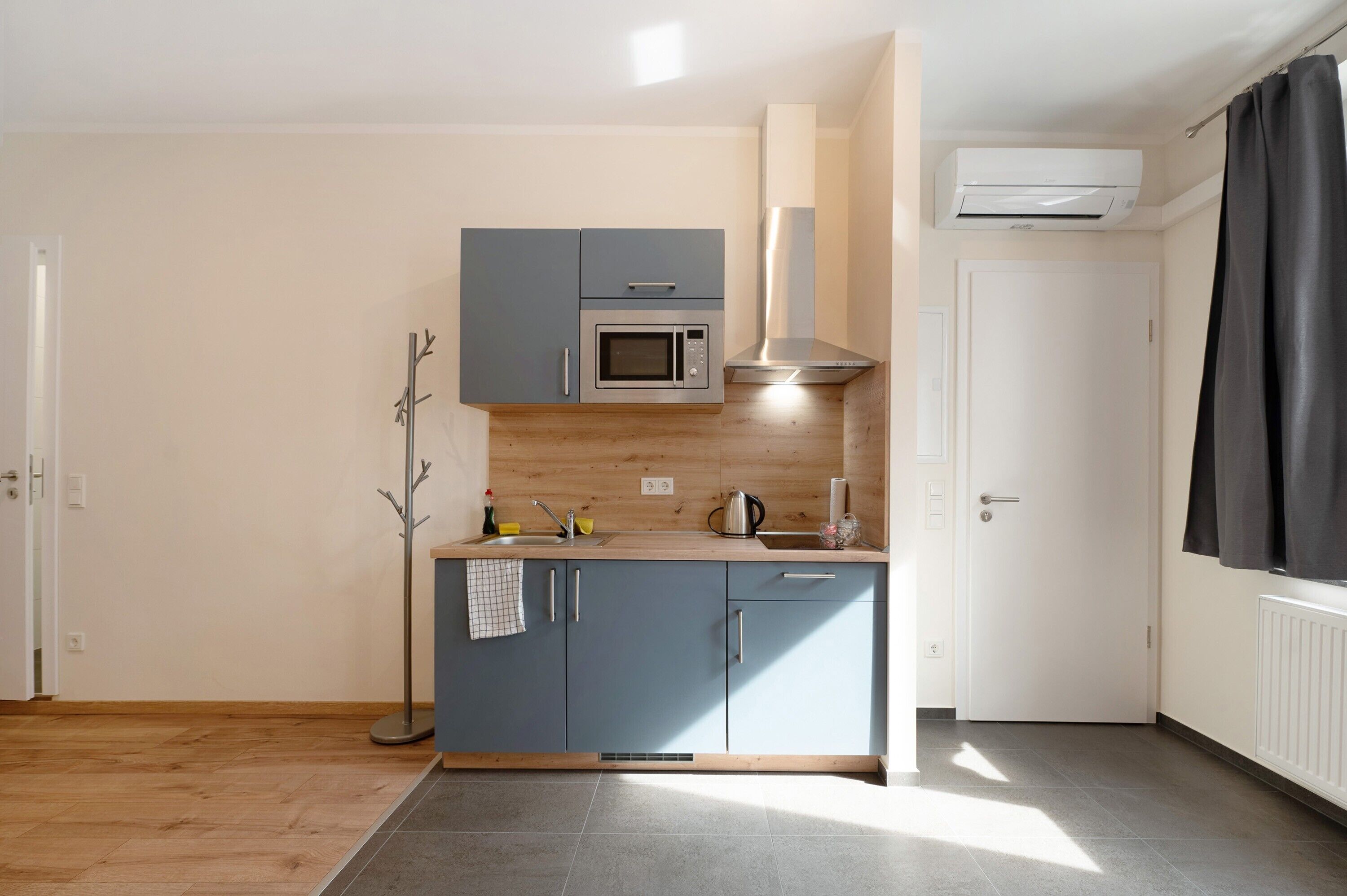 Une cuisine compacte équipée d’un four à micro-ondes, d’une cuisinière et d’un four encastré.