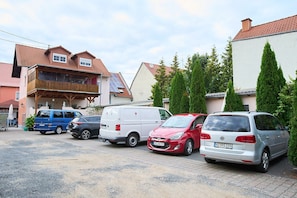 A parking area with several cars and a building with a sloped roof.