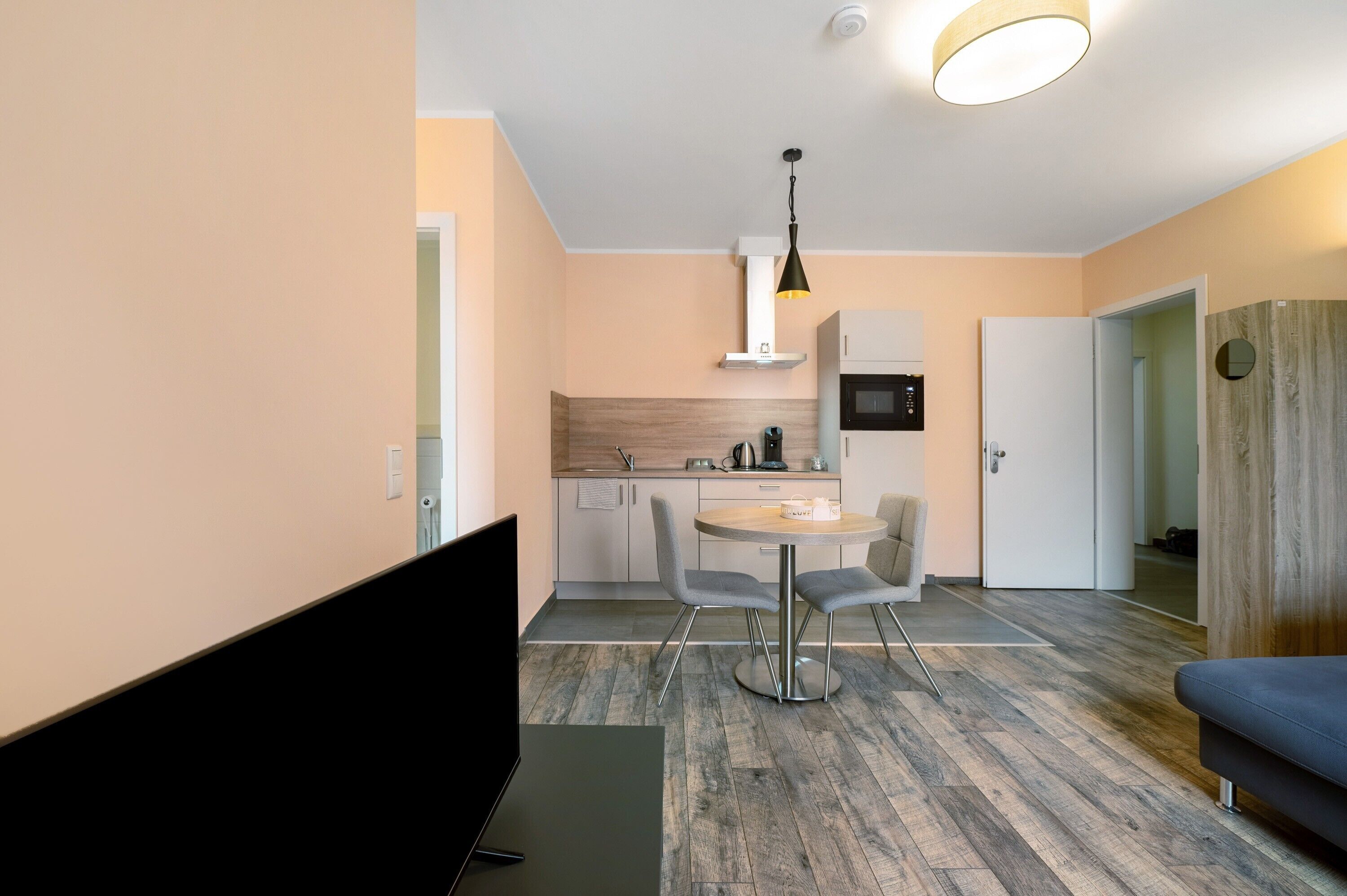 Een moderne keuken met een eethoek, een flatscreen televisie en een bank.