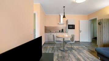 A modern kitchen with a dining area, a flat-screen TV, and a sofa.