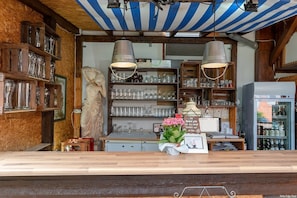 A bar area with wooden shelves, a statue, and a refrigerator stocked with bottles.