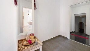 Ein Flur mit einem Spiegel, einem kleinen Tisch mit einer Buddha-Statue und einem roten Teppich, der zu einer Tür führt.