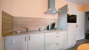 Uma cozinha moderna com uma pia de aço inoxidável, chaleira, cafeteira e micro-ondas.
