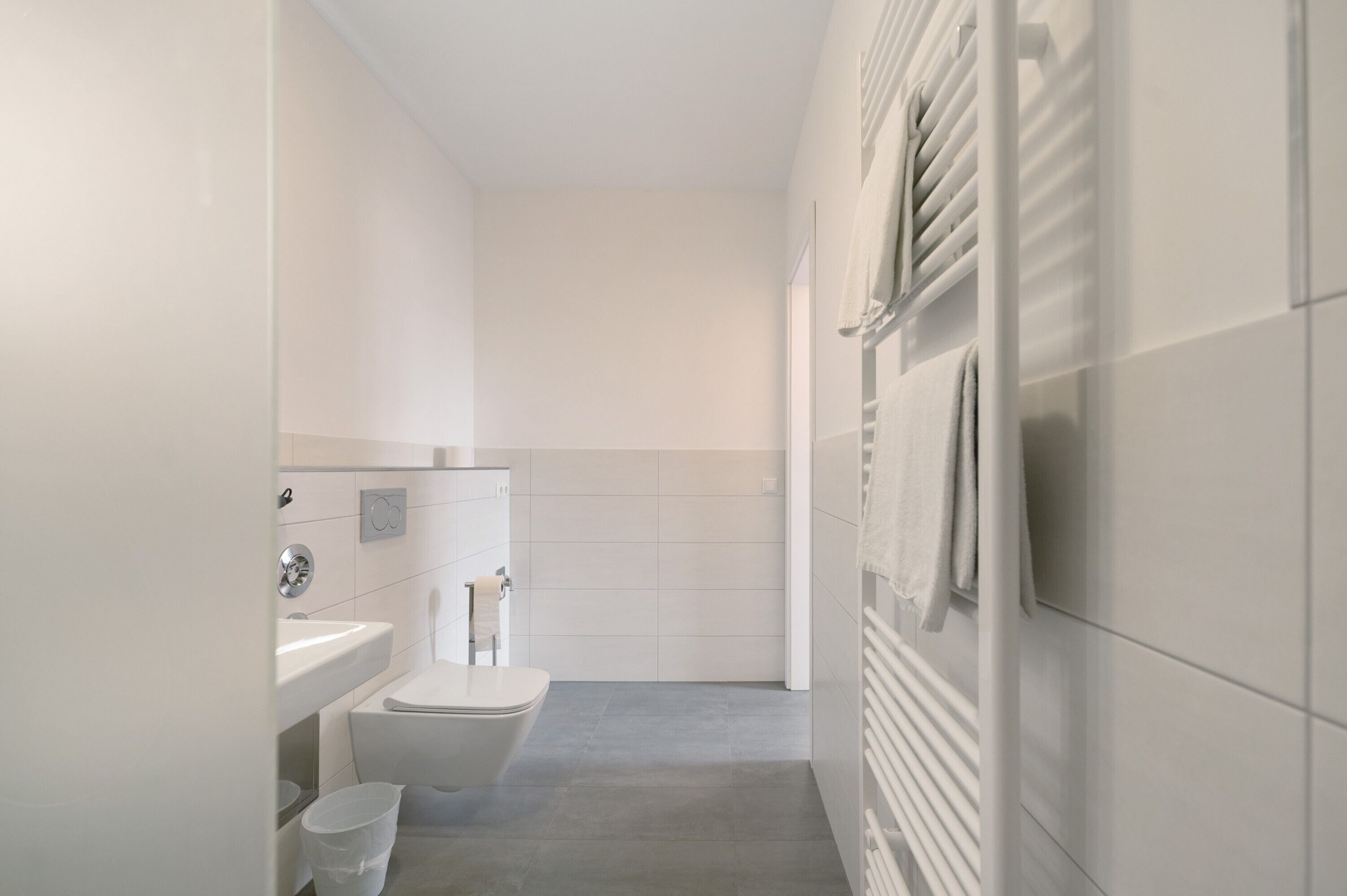 A modern bathroom with a toilet, sink, and towel rack.