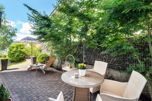 A patio with wicker furniture, a round glass table, and potted plants. - Apartment 'Beas Ferienglück' with Private Terrace and Wi-Fi (Busenberg)