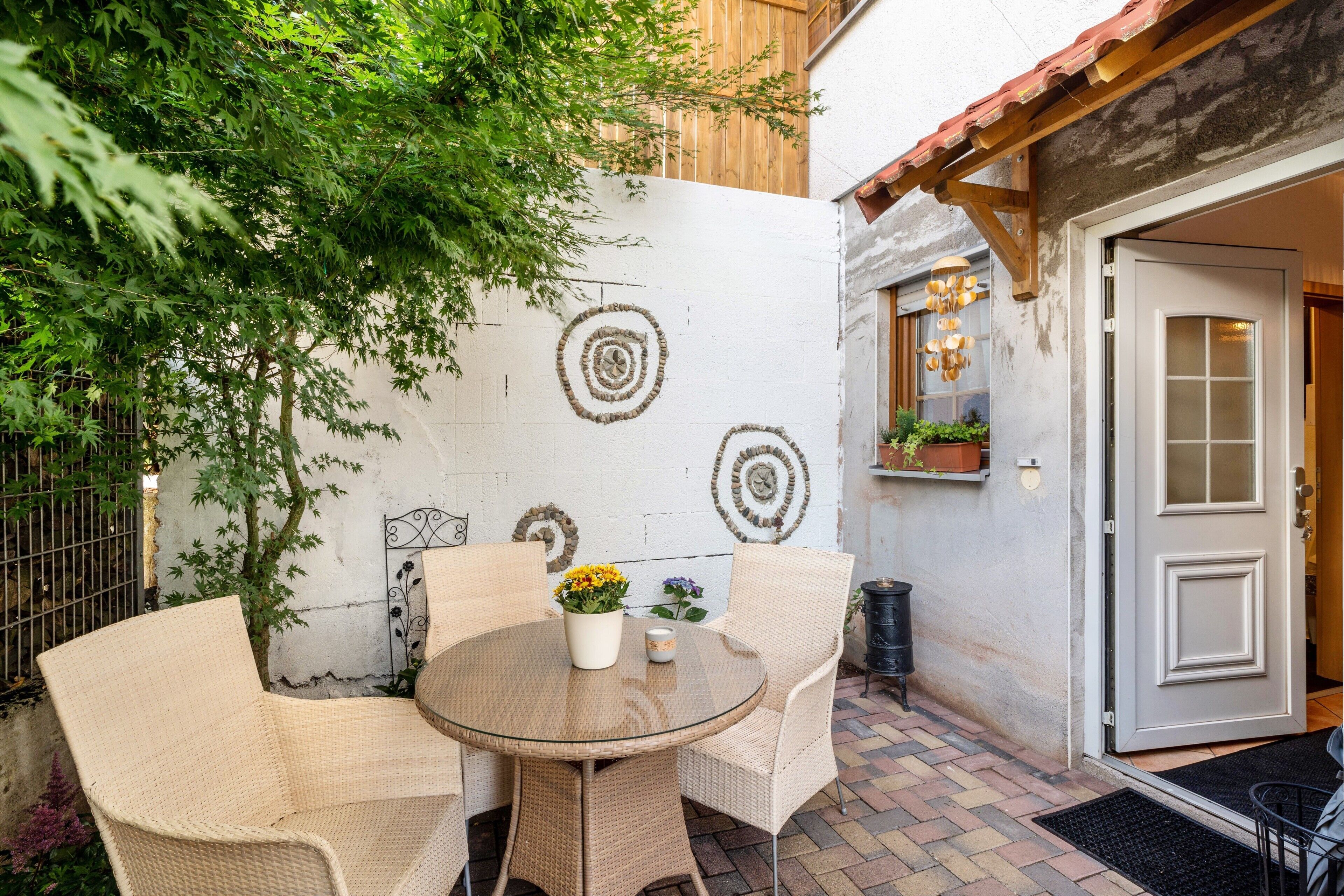 Eine Terrasse mit Korbmöbeln, einem runden Tisch und einem Blumentopf.