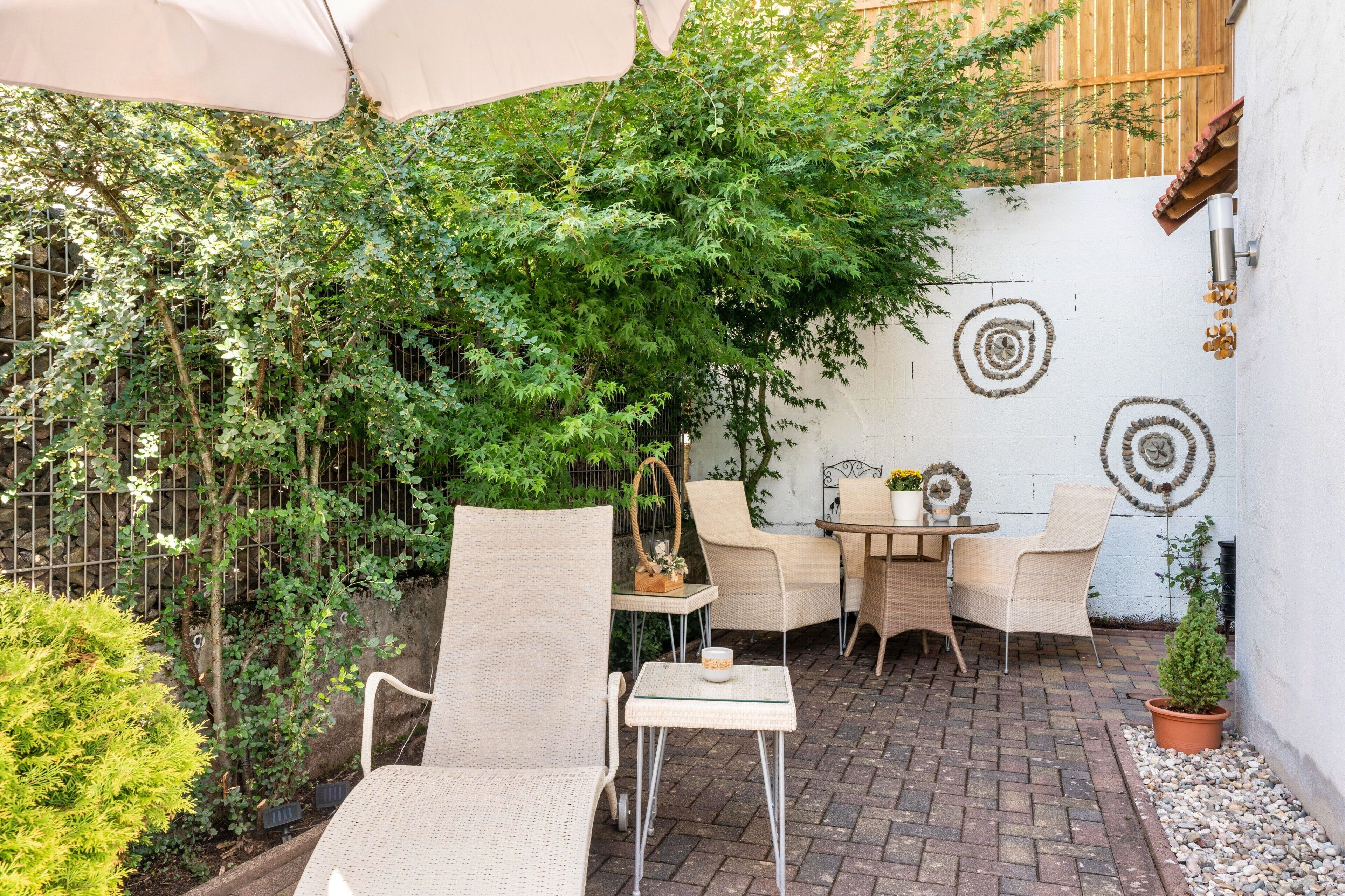 Un espace extérieur aménagé avec des chaises en osier, une petite table et une plante en pot.