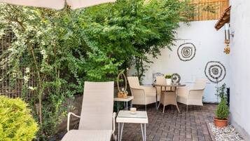 Un espace extérieur aménagé avec des chaises en osier, une petite table et une plante en pot.