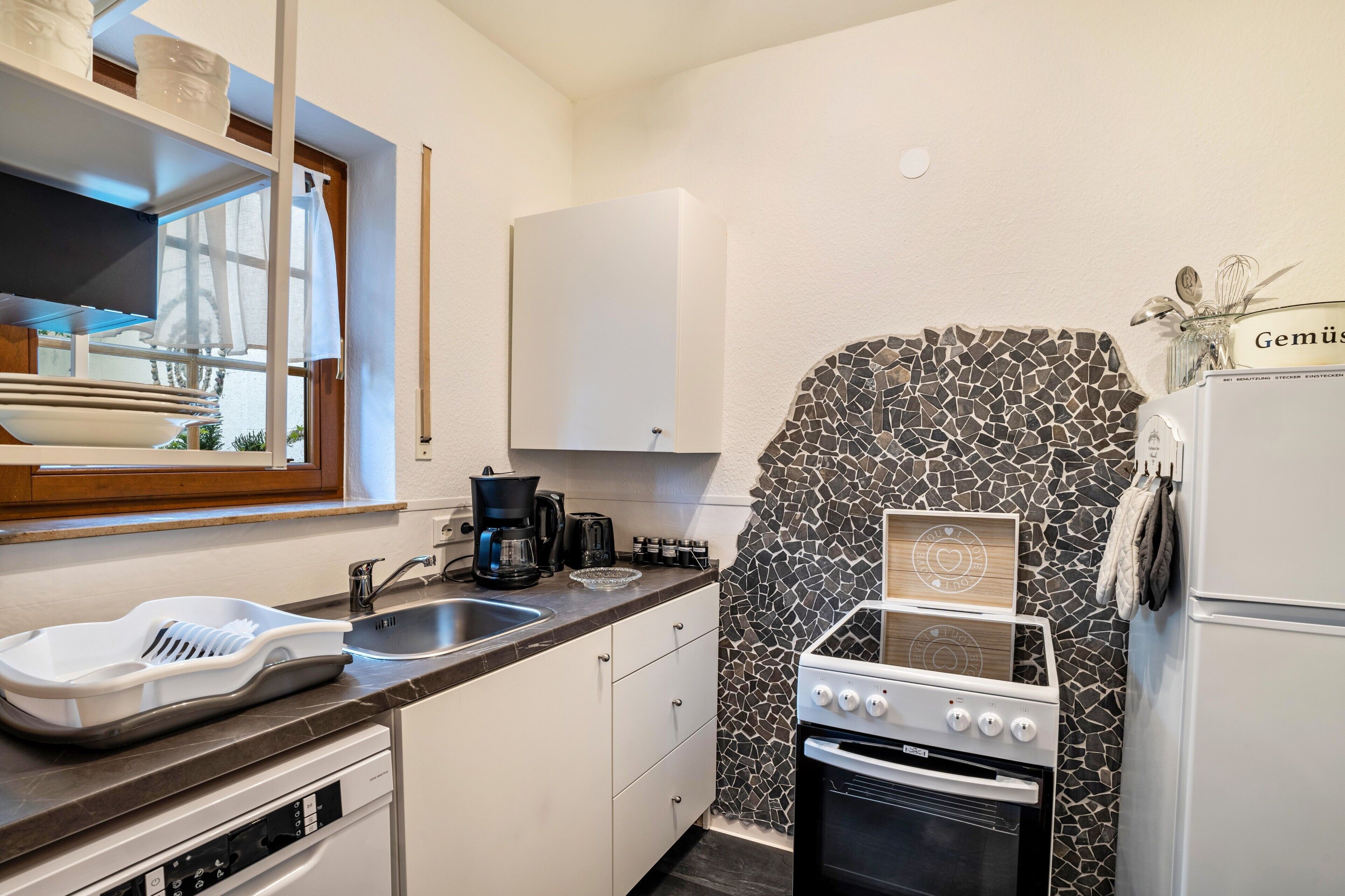 A compact kitchen with a sink, stove, and white cabinets.