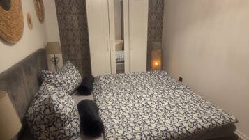Ein Schlafzimmer mit Bett, Kissen, Kleiderschrank, Lampe und Wandbild.