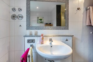 Une salle de bain avec un lavabo blanc, un miroir encadré de granit et un porte-serviettes.