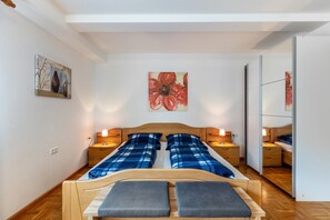 Une chambre à coucher avec un lit, des tables de chevet, un miroir et des œuvres d’art accrochées aux murs.