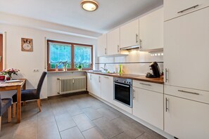 Une cuisine moderne avec des armoires blanches, un plan de travail en bois et un four encastré.