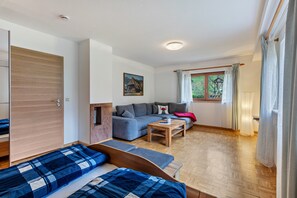 Une pièce comprenant un lit, un canapé, une petite table et une fenêtre avec des rideaux.