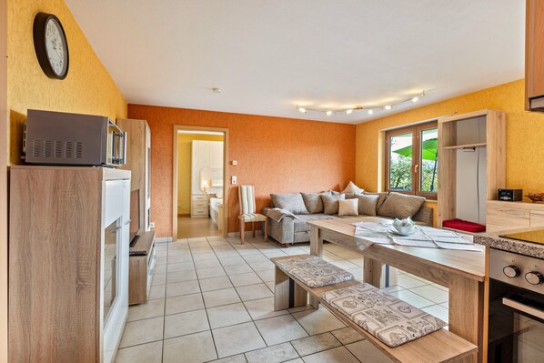 A modern kitchen with a dining area, a sofa, and a clock on the wall. - Apartment 'Landblick' with Mountain View, Private Terrace and Wi-Fi (Zell im Wiesental)