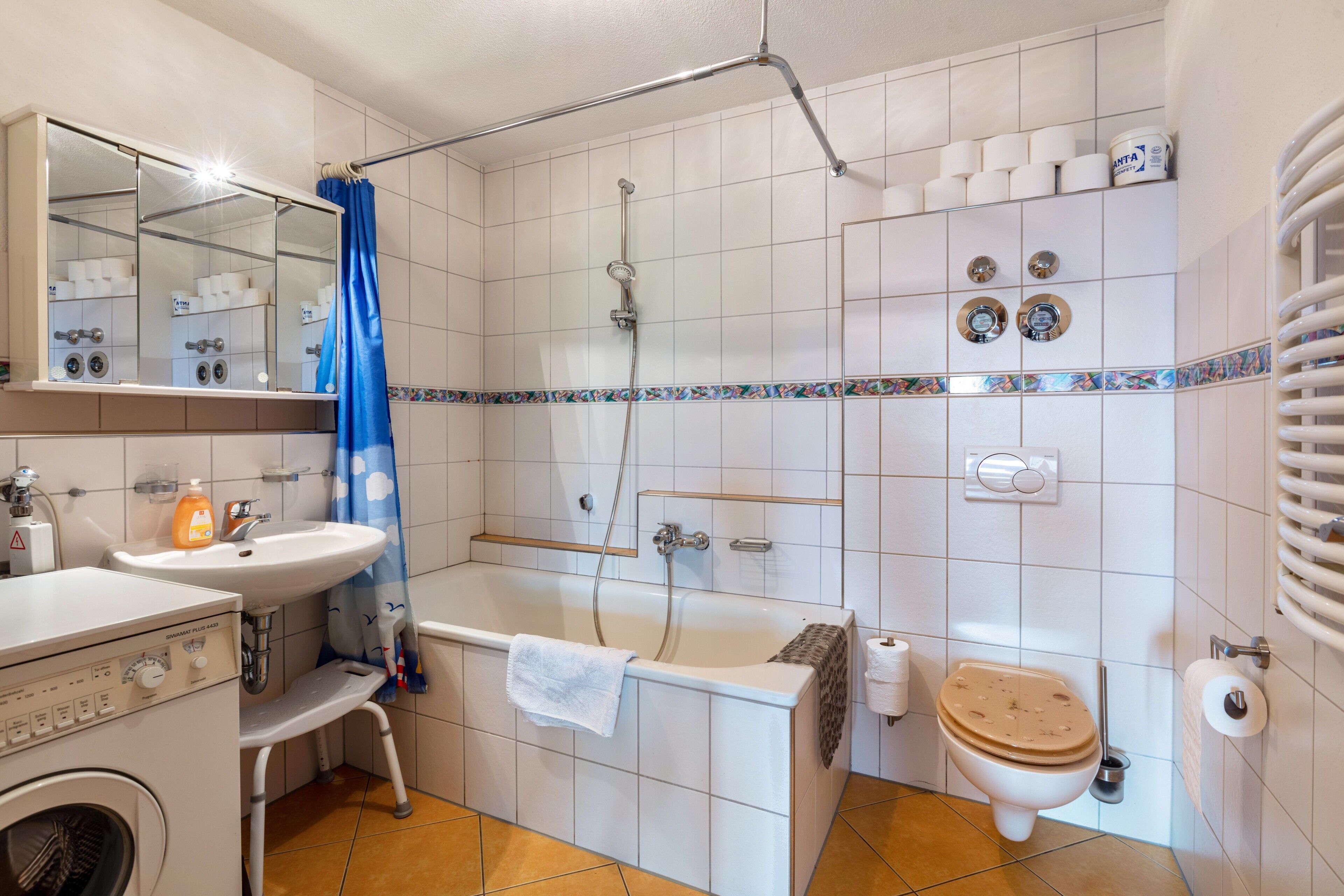 Une salle de bain équipée d’une baignoire, de toilettes, d’un lavabo et d’un lave-linge.