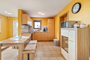 A compact kitchen with wooden cabinets, a microwave, and a clock on the wall. - Apartment 'Landblick' with Mountain View, Private Terrace and Wi-Fi (Zell im Wiesental)