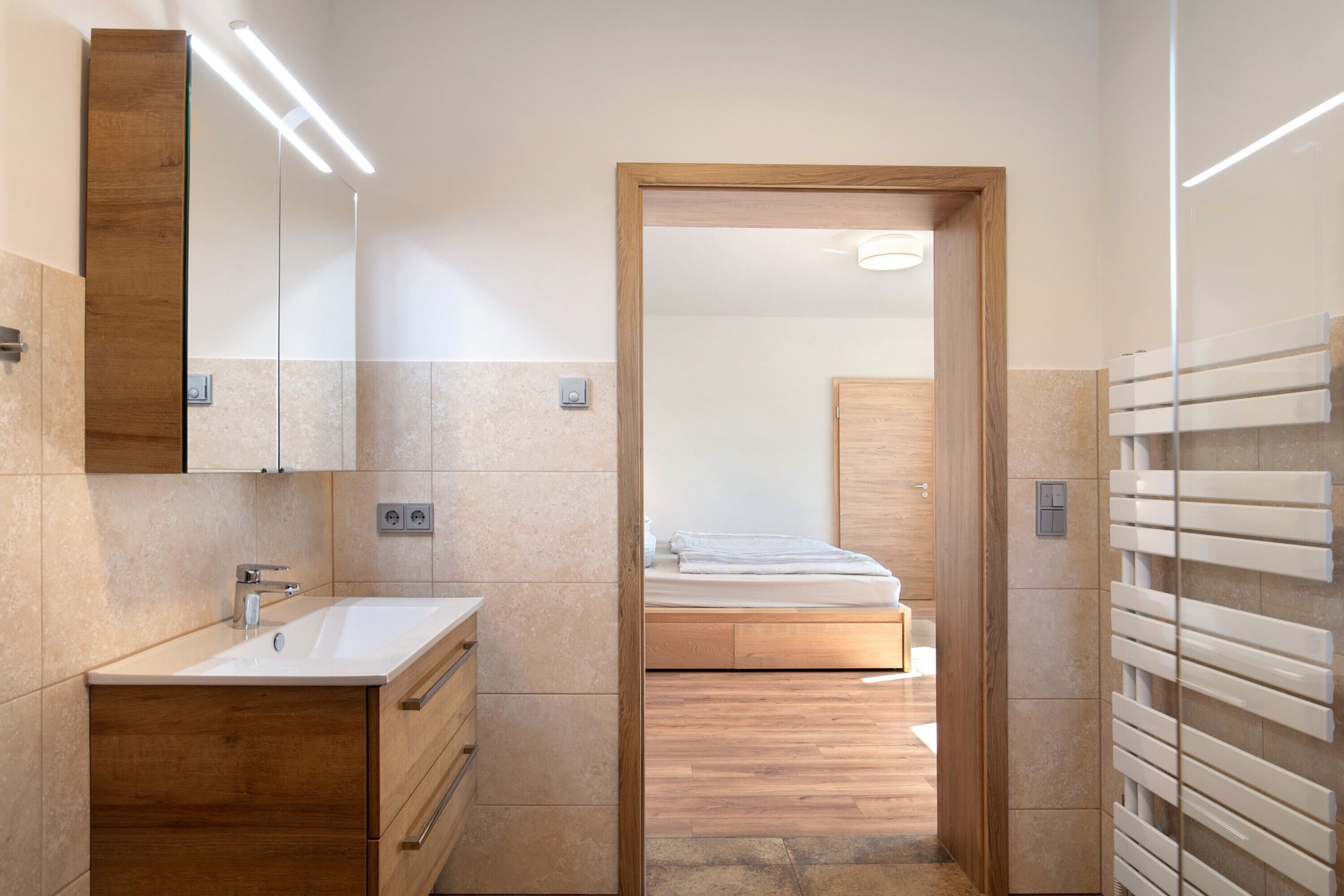 Un baño moderno con tocador de madera, un espejo y zona de ducha.