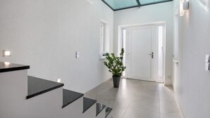 Un interior moderno con una escalera, una planta en maceta y una puerta que da a otra habitación.