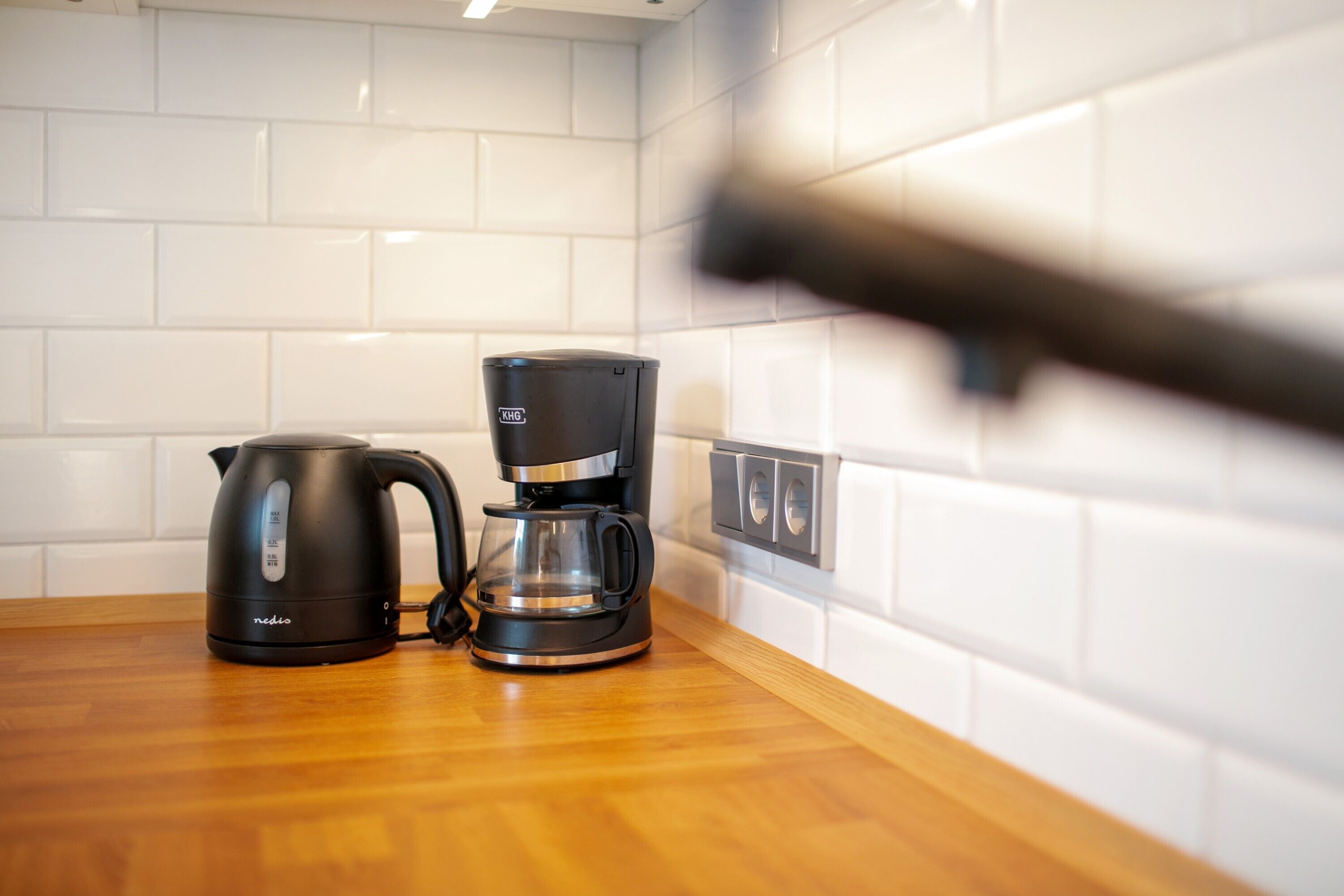 A kitchen with a coffee maker and a kettle on a wooden countertop.