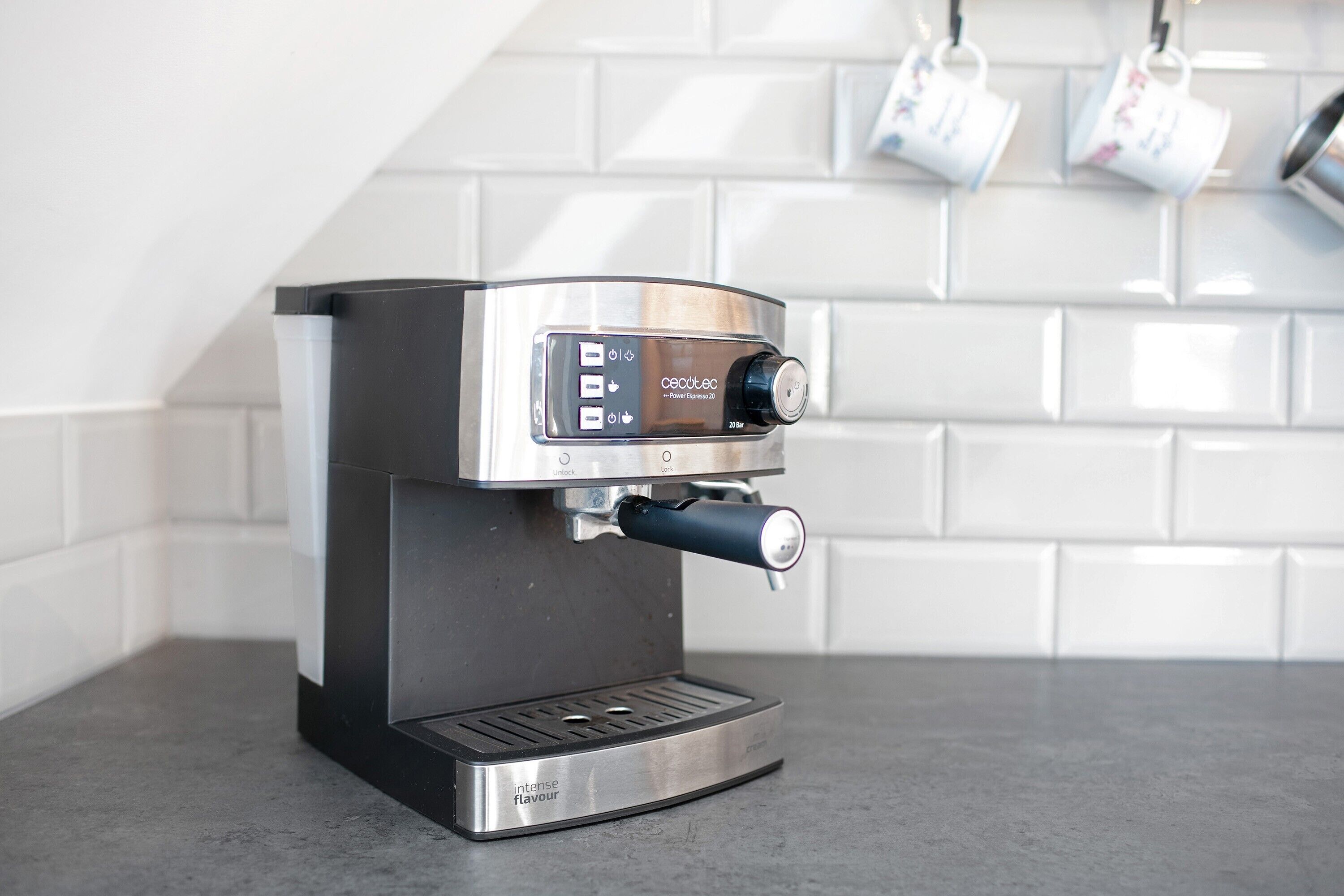 A modern espresso machine with a digital interface, placed on a countertop with a tiled backsplash.
