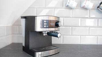 A modern espresso machine with a digital interface, placed on a countertop with a tiled backsplash.