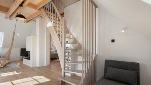 A modern interior with a wooden staircase, a sofa, and a hanging chair. - Apartment 'Flieder' with Shared Garden, Balcony and Wi-Fi (Lunow-Stolzenhagen)