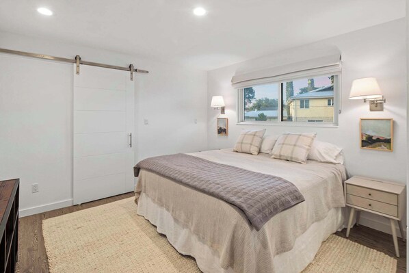 A bedroom with a bed, bedside lamps, a window, and a wardrobe.