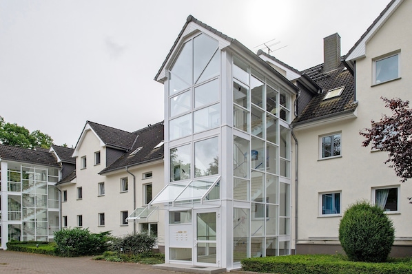 Un bâtiment moderne doté d’une façade en verre, de nombreuses fenêtres et d’un escalier apparent menant à un étage supérieur.