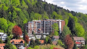 A hotel with multiple floors, surrounded by trees and residential buildings. - Apartment No. 19 with Shared Garden, Balcony and Wi-Fi (Bad Herrenalb)