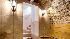 Zona de sauna con paredes de piedra, bancos e iluminación empotrada.