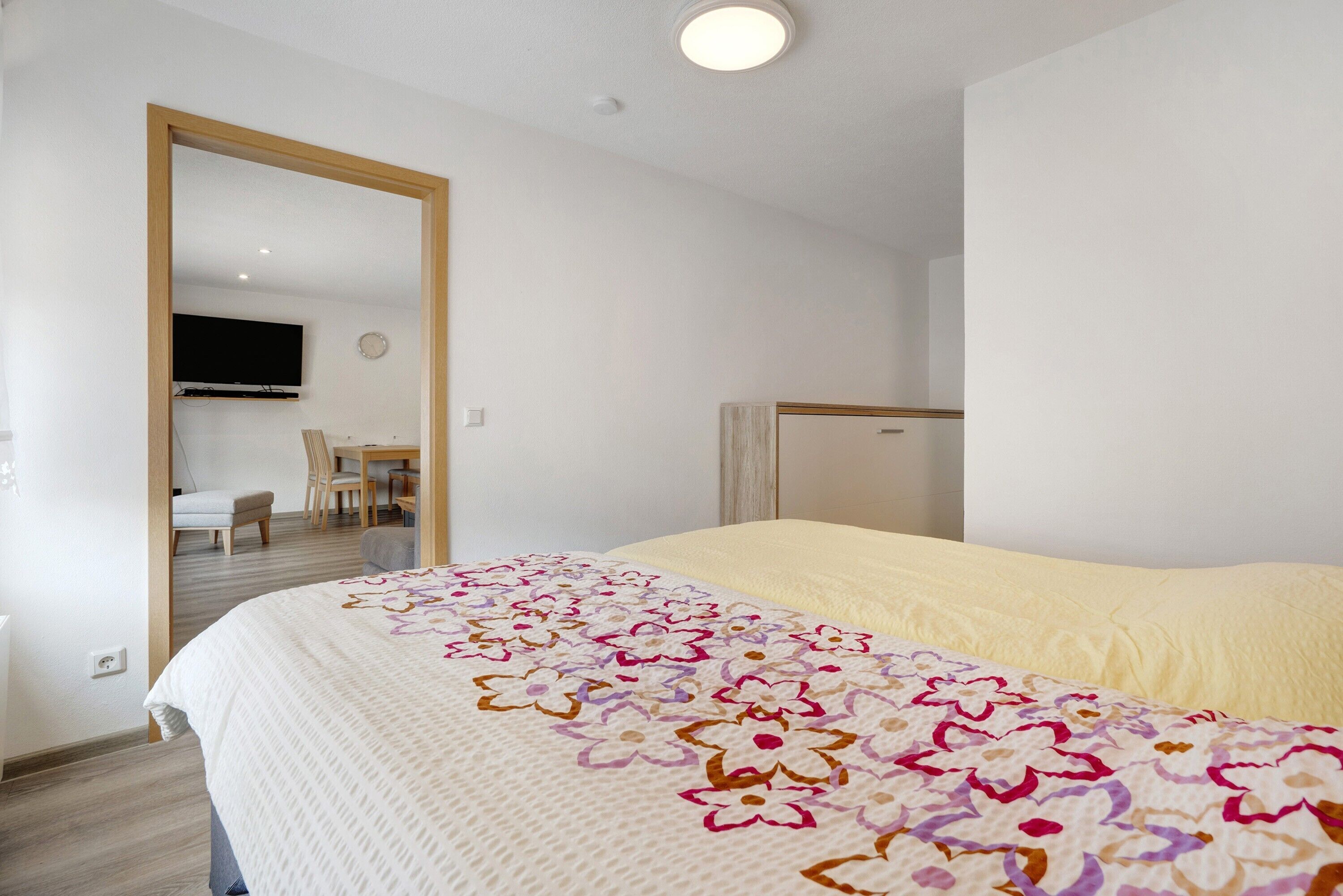 Ein Schlafzimmer mit einem Bett, einem Fernseher, einem Schreibtisch und einem Sessel.