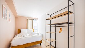 Un dormitorio con cama de madera, armario metálico y una mesita de noche pequeña.