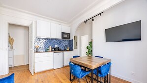 Una cocina moderna con armarios blancos, un salpicadero azul tipo espiga y una mesa de comedor de madera con sillas azules.